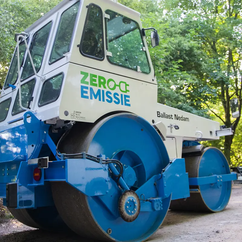 Bos met blauw witte asfaltwals met letters Zero Emissie op de zijkant
